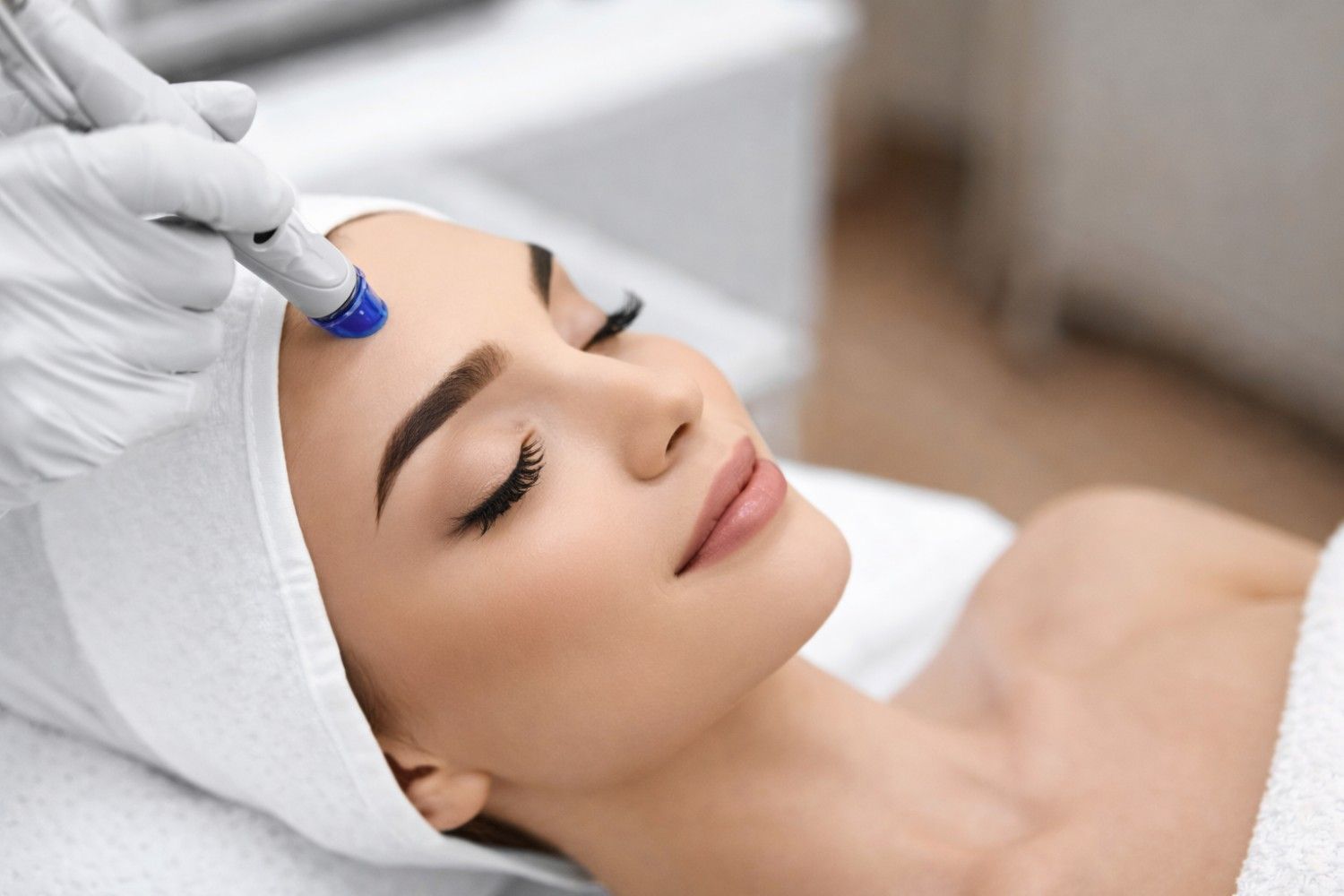 Hydrafacial treatment device applied on forehead for deep skin cleansing and exfoliation