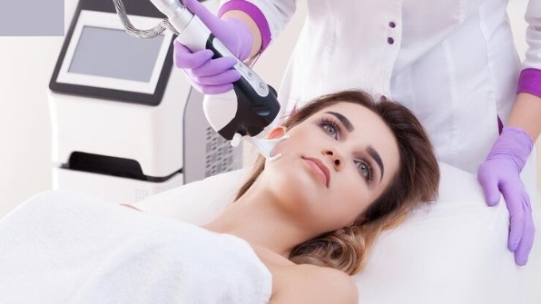 Patient receiving pico laser facial treatment for acne scars with advanced laser device in a professional clinic
