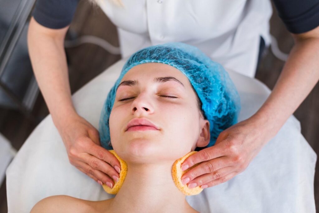 Woman receiving professional facial treatment at a medical spa, esthetician performing skincare facial with cleansing sponges in clinic.